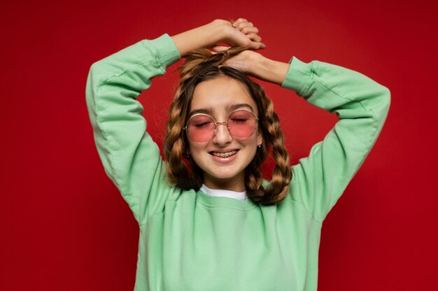 Retrato de uma adolescente segurando suas tranças e usando óculos escuros