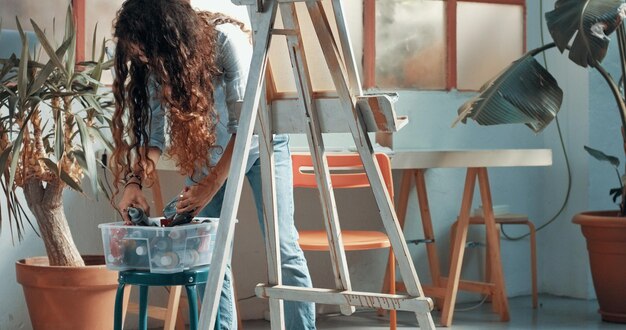 Retrato de uma bela artista feminina de cabelos compridos no trabalho em sua tela em um estúdio