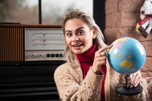 Retrato de uma bela dama apontando para um globo do mundo