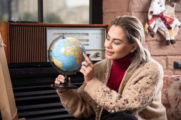 Retrato de uma bela dama apontando para um globo do mundo