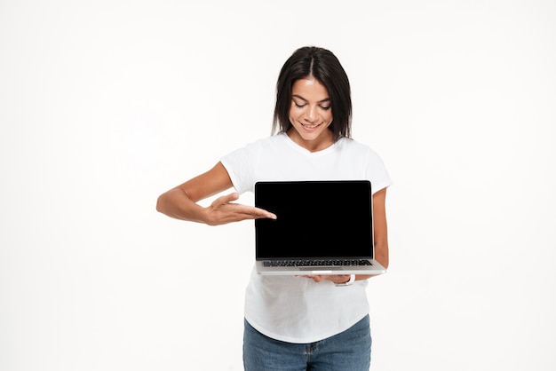 Foto grátis retrato de uma bela jovem apresentando laptop de tela em branco