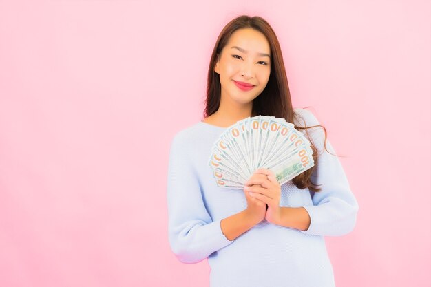Retrato de uma bela jovem asiática com muito dinheiro e muito dinheiro na parede cor de rosa