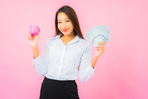 Retrato de uma bela jovem asiática com muito dinheiro e muito dinheiro na parede rosa