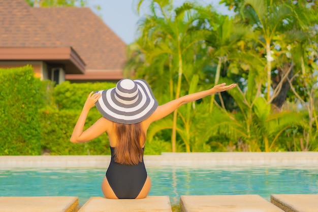 Retrato de uma bela jovem asiática relaxando ao redor da piscina em um hotel resort de férias