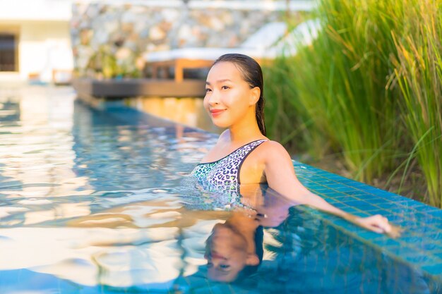Retrato de uma bela jovem asiática relaxando ao redor da piscina em um hotel resort de férias