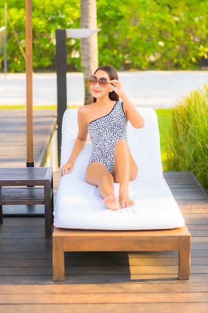 Retrato de uma bela jovem asiática relaxando ao redor da piscina em um hotel resort de férias