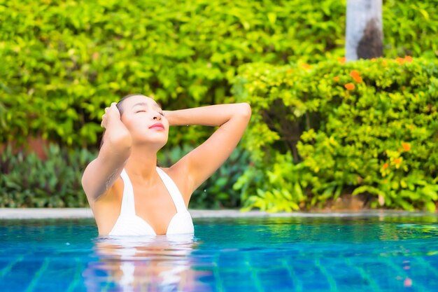 Retrato de uma bela jovem asiática relaxando ao redor da piscina em um hotel resort de férias