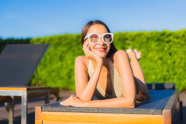 Foto grátis retrato de uma bela jovem asiática relaxando ao redor de uma piscina em um resort de hotel