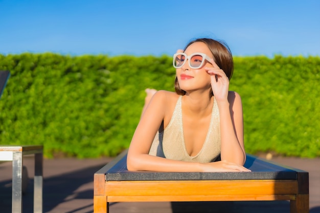 Foto grátis retrato de uma bela jovem asiática relaxando ao redor de uma piscina em um resort de hotel