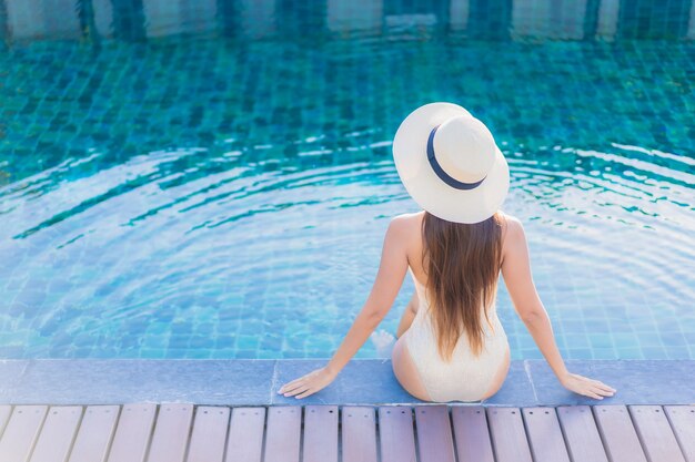 Retrato de uma bela jovem asiática relaxando ao redor de uma piscina em um resort de hotel