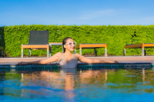 Retrato de uma bela jovem asiática relaxando ao redor de uma piscina em um resort de hotel