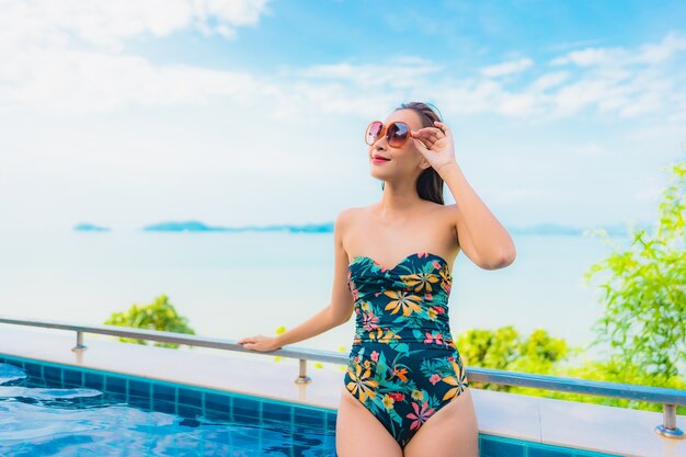 Retrato de uma bela jovem asiática relaxando em uma piscina com vista para o mar