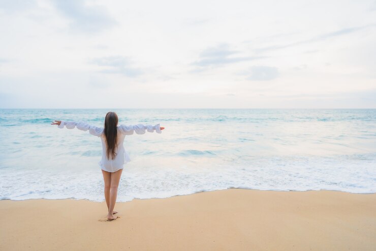 Foto grátis retrato de uma bela jovem asiática relaxando em uma praia ao ar livre em viagens de férias