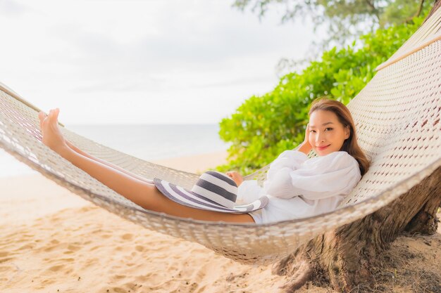 Retrato de uma bela jovem asiática relaxando em uma rede ao redor da praia nas férias