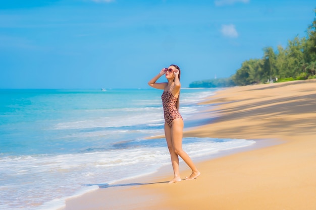 Foto grátis retrato de uma bela jovem asiática relaxando na praia com nuvens brancas no céu azul em viagens de férias