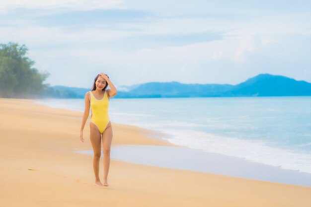 Retrato de uma bela jovem asiática relaxando na praia em viagens de férias