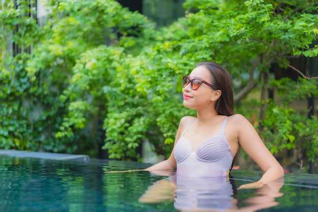 Retrato de uma bela jovem asiática relaxando, sorrindo, lazer ao redor de uma piscina externa em um hotel resort