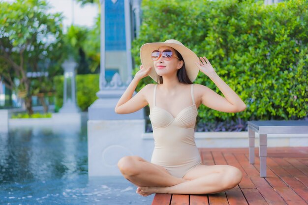 Retrato de uma bela jovem asiática relaxando um sorriso ao redor de uma piscina em um hotel resort em uma viagem de férias