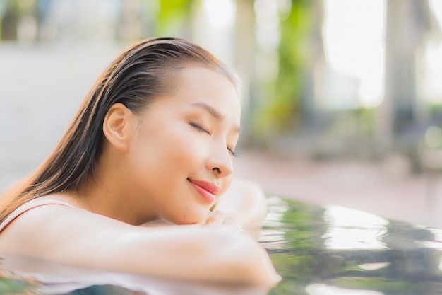 Retrato de uma bela jovem asiática relaxando um sorriso ao redor de uma piscina em um hotel resort em uma viagem de férias