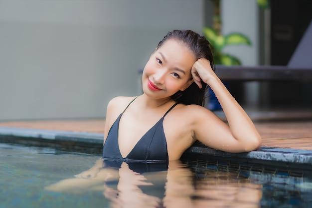 Retrato de uma bela jovem asiática relaxando um sorriso ao redor de uma piscina em um hotel resort