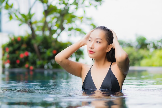 Retrato de uma bela jovem asiática relaxando um sorriso ao redor de uma piscina em um hotel resort