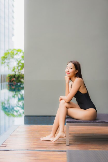 Retrato de uma bela jovem asiática relaxando um sorriso ao redor de uma piscina em um hotel resort