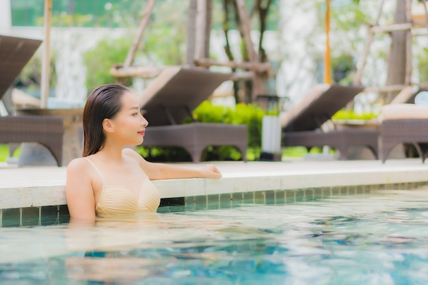 Retrato de uma bela jovem asiática relaxando um sorriso ao redor de uma piscina em um hotel resort