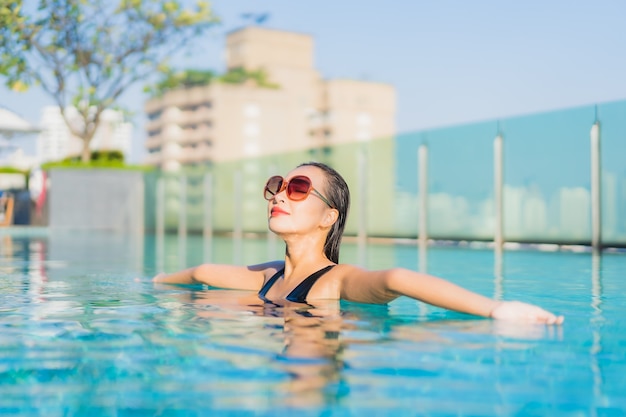 Retrato de uma bela jovem asiática relaxando um sorriso ao redor de uma piscina em um hotel resort