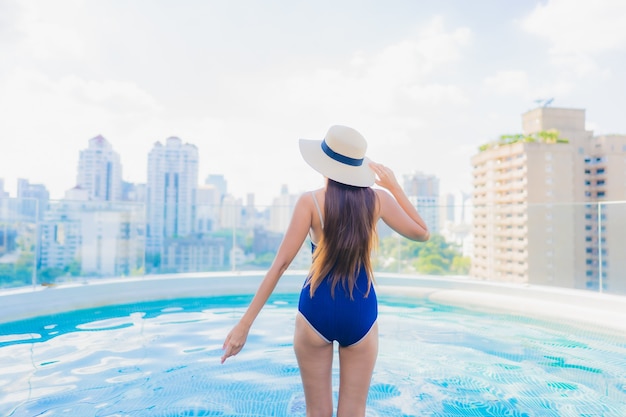 Retrato de uma bela jovem asiática relaxando um sorriso ao redor de uma piscina em um hotel resort