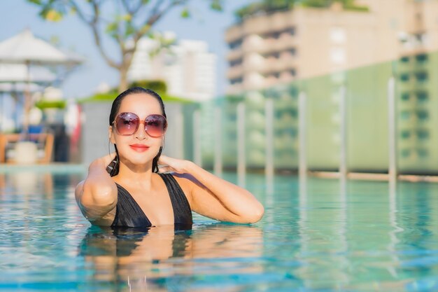 Retrato de uma bela jovem asiática relaxando um sorriso ao redor de uma piscina em um hotel resort