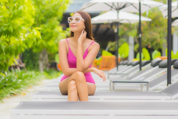 Retrato de uma bela jovem asiática relaxando um sorriso ao redor de uma piscina em um hotel resort