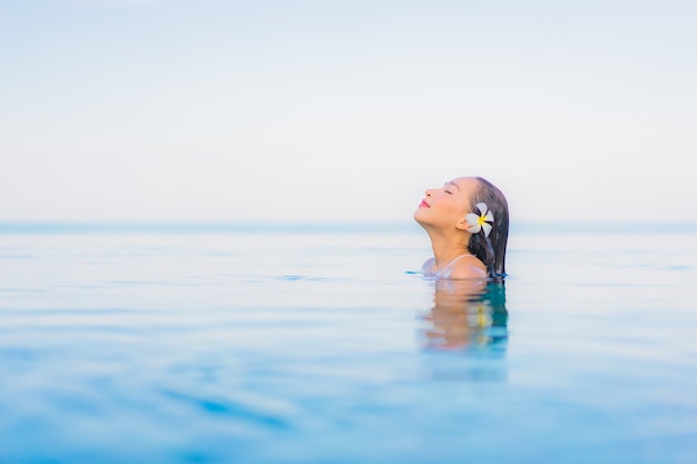 Retrato de uma bela jovem asiática relaxando um sorriso ao redor de uma piscina em um hotel resort