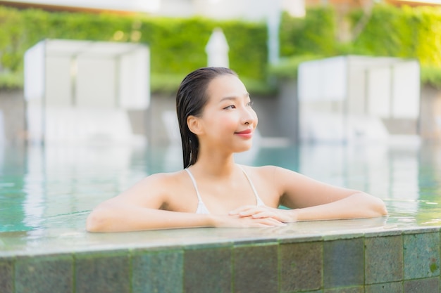 Retrato de uma bela jovem asiática relaxando um sorriso ao redor de uma piscina em um hotel resort