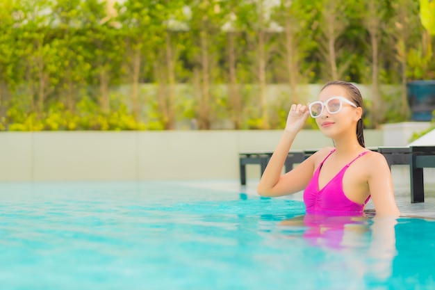Foto grátis retrato de uma bela jovem asiática relaxando um sorriso ao redor de uma piscina em um hotel resort
