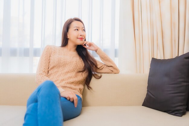 Retrato de uma bela jovem asiática relaxando um sorriso feliz no interior da decoração do sofá do quarto