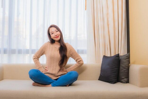 Retrato de uma bela jovem asiática relaxando um sorriso feliz no interior da decoração do sofá do quarto