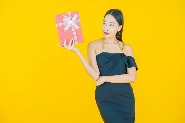 Retrato de uma bela jovem asiática sorrindo com caixa de presente vermelha