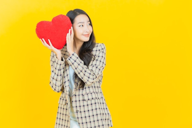 Retrato de uma bela jovem asiática sorrindo com formato de almofada em forma de coração