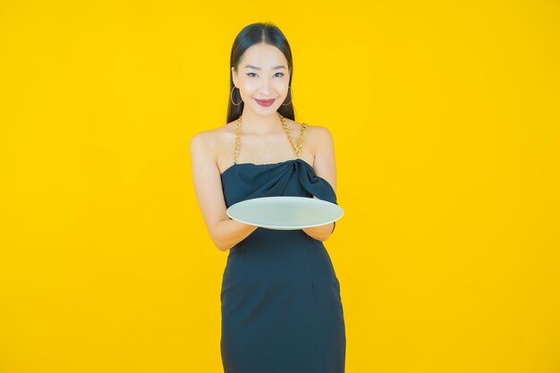 Retrato de uma bela jovem asiática sorrindo com prato vazio