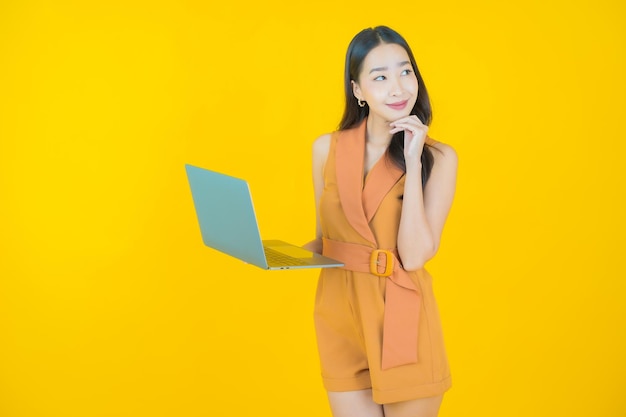 Retrato de uma bela jovem asiática sorrindo com um computador laptop Foto gratuita