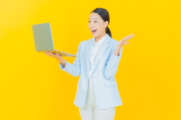 Retrato de uma bela jovem asiática sorrindo com um laptop no fundo isolado.