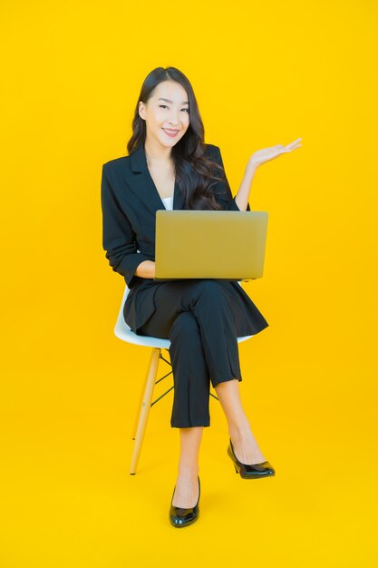 Retrato de uma bela jovem asiática sorrindo com um laptop no fundo isolado.