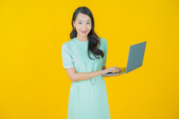 Retrato de uma bela jovem asiática sorrindo com um laptop no fundo isolado.