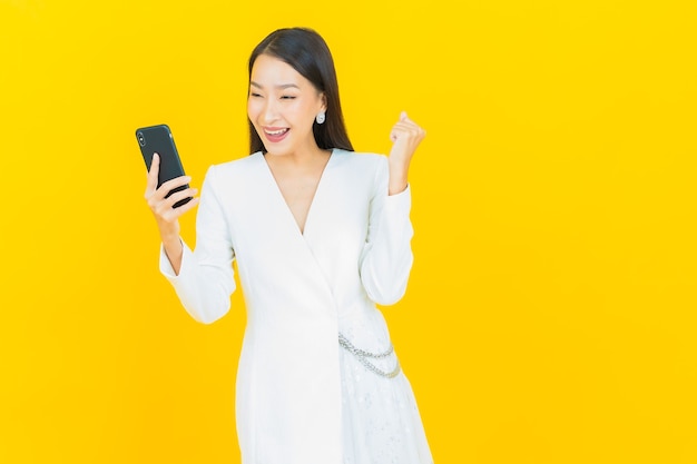 Retrato de uma bela jovem asiática sorrindo com um telefone celular inteligente