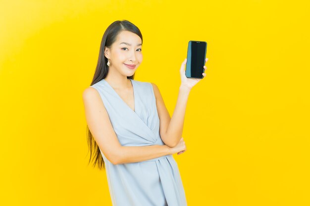 Retrato de uma bela jovem asiática sorrindo com um telefone celular inteligente