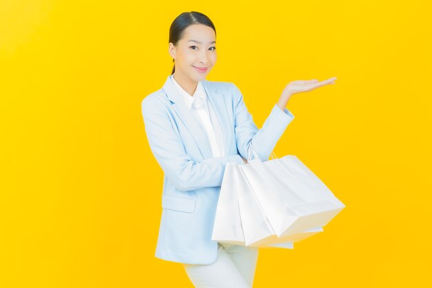 Retrato de uma bela jovem asiática sorrindo com uma sacola de compras em amarelo.