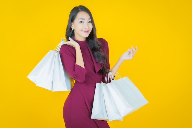 Retrato de uma bela jovem asiática sorrindo com uma sacola de compras em amarelo.