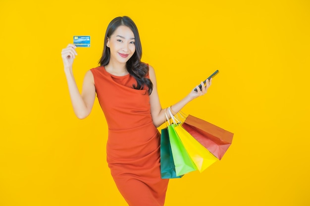 Retrato de uma bela jovem asiática sorrindo com uma sacola de compras em amarelo