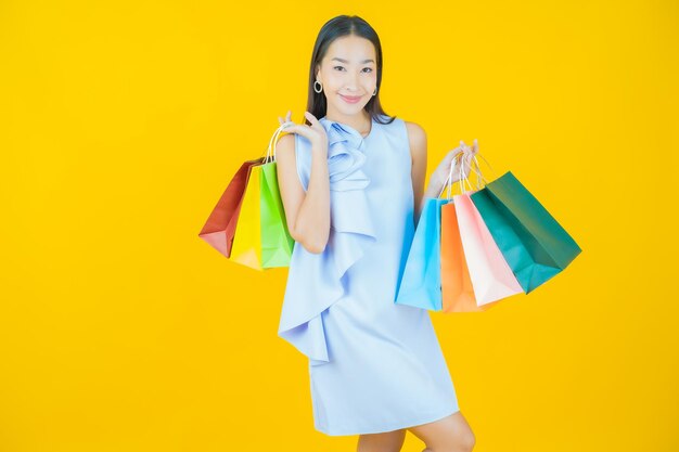 Retrato de uma bela jovem asiática sorrindo com uma sacola de compras em amarelo.