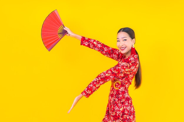 Retrato de uma bela jovem asiática sorrindo em ação no conceito de ano novo chinês na parede colorida